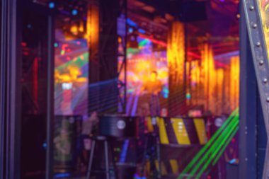 Disko ışıkları olan bulanık bir gece kulübü. Renkli iç mekanın soyut odaklanmış arka planı. DJ sahneden müzik çalar