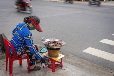 Asyalı kadın şehir yolunda geleneksel çerez pişiriyor. Şerbetli kızarmış muz, egzotik yemekler. Nha Trang, Vietnam. 