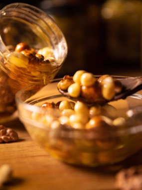 Fındıkla karıştırılmış bal, şeffaf bir kavanozdan cam bir tabağa dökülen tohumlar. natürmort