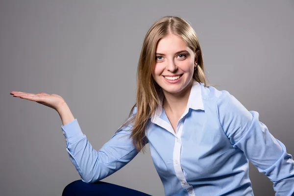 Jovem mulher mostrando produto — Fotografia de Stock