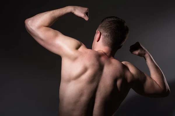 Muskelprotz zeigt seinen Bizeps zurück. — Stockfoto