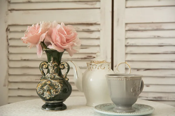Sobre la mesa el juego de té y las flores en el florero — Foto de Stock