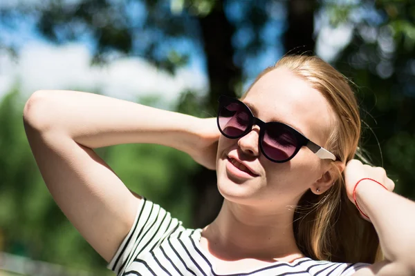 Jonge vrouw in zonnebril op een achtergrond van de natuur — Stockfoto