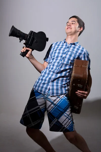 Portrét mladé kameraman s starých filmová kamera a suitca — Stock fotografie