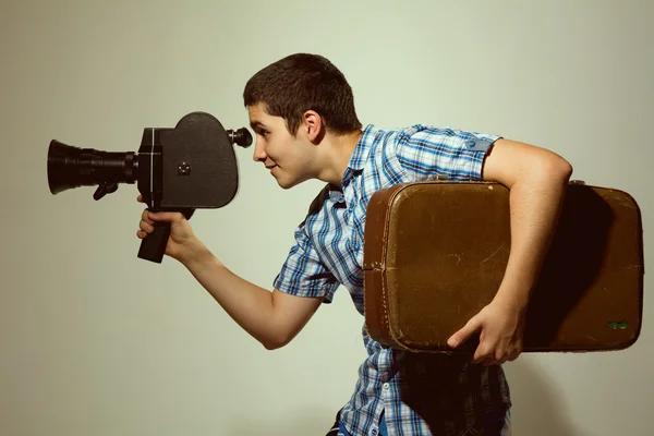 Young gay filmmaker with old movie camera and a suitcase in his — Stock Photo, Image