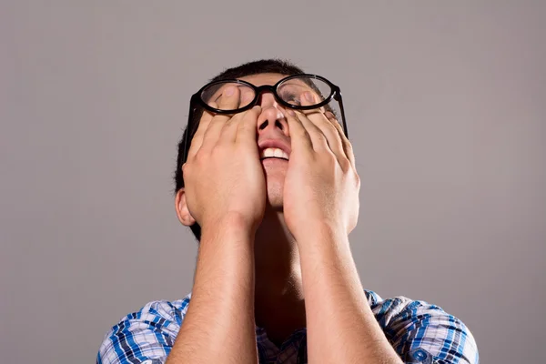 Mladý muž brýle schovává hlavu v dlaních — Stock fotografie
