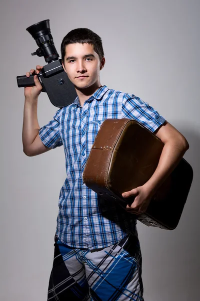 Young man filmmaker with old movie camera and a suitcase in his — Stock Photo, Image