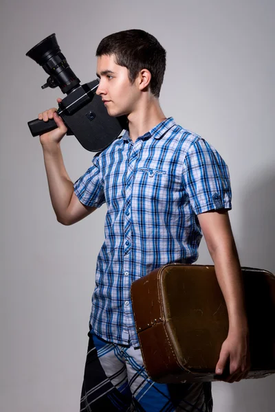 Young man filmmaker with old movie camera and a suitcase in his — Stock Photo, Image