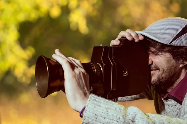 Um homem usando um boné com uma câmera de filme antiga . — Fotografia de Stock