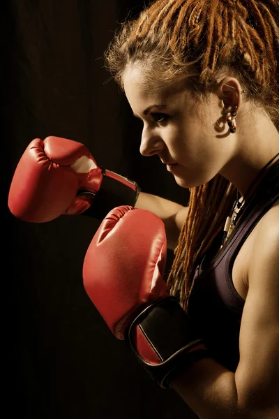 Beautiful woman with red boxing gloves, dreadlocks on a black ba — Stock Photo, Image