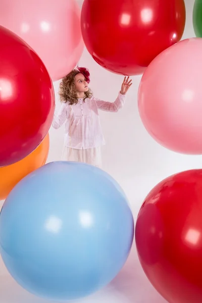 Beautiful girl in a white blouse is considering large balloons. — Stock Photo, Image