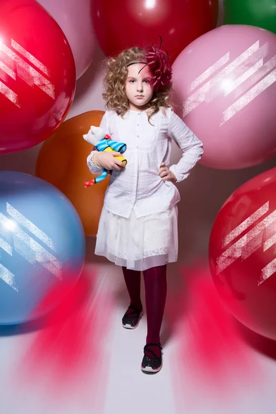 Menina bonita em uma blusa branca com um brinquedo macio vem à câmera — Fotografia de Stock