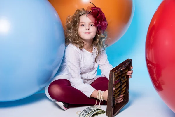 Girl schoolgirl with wooden abacus and a wad of dollars. — Stock Photo, Image