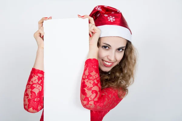 Vrolijk meisje in een rode jurk in KERSTMUTS houden spandoeken. — Stockfoto