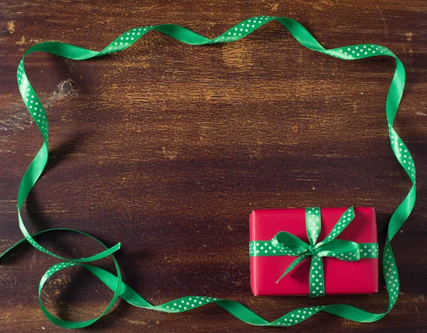 Boîte cadeau rouge avec ruban vert couché sur le fond en bois — Photo