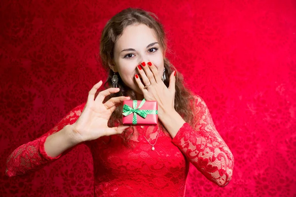 Menina entusiasta bonita com um pequeno presente em um vestido vermelho — Fotografia de Stock