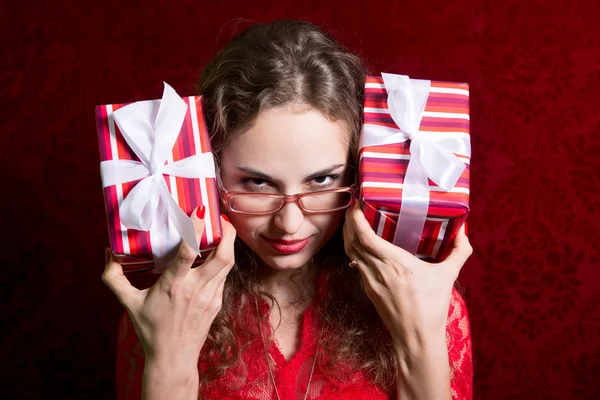 Jovem mulher em óculos com duas caixas de presente listradas olha em t — Fotografia de Stock