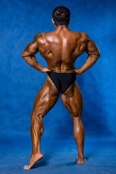 Athletic sports bodybuilder demonstrates posture from the back — Stock Photo, Image