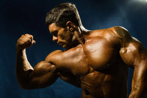 Bonito fisiculturista muscular demonstra seus músculos . — Fotografia de Stock