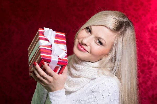 A girl in a white sweater and striped gift with white bow lookin — Stock Photo, Image