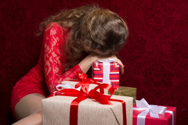 Girl with gifts and face covered with a red background — Stock Photo, Image