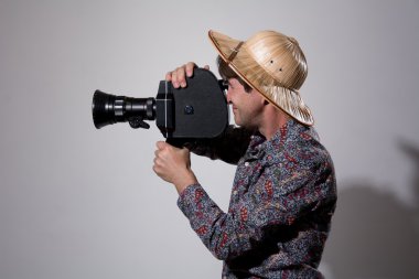 Gri bir backgrou üzerinde eski bir film kamera ile Hasır Şapkalı bir adam