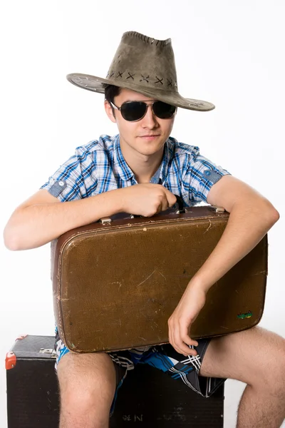 Portret van een jonge man in zonnebril met een koffer — Stockfoto