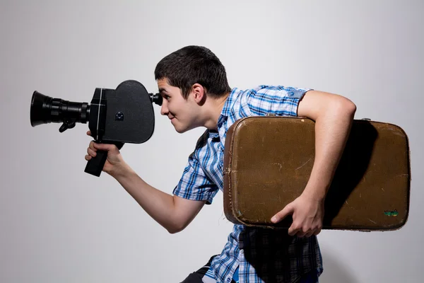 Young male filmmaker with old movie camera and a suitcase in his — Stock Photo, Image