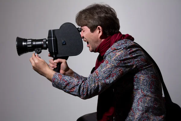 Un hombre con una vieja cámara de cine sobre un fondo gris . — Foto de Stock