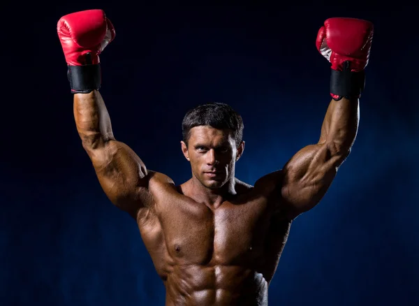 Strong muscular boxer in red boxing gloves raised his hands abov — Stock Photo, Image