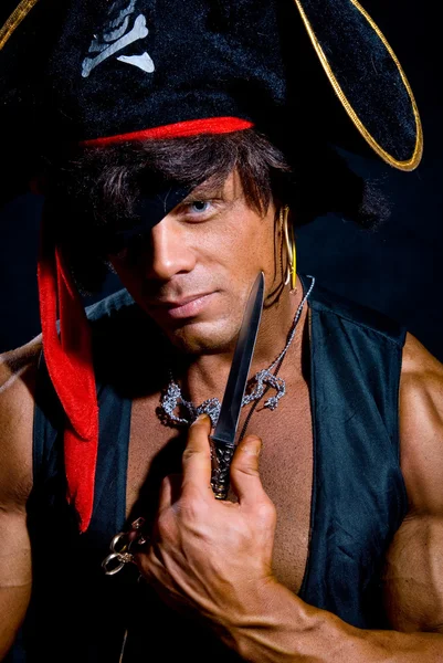 Close-up portrait muscular pirate with a knife on a dark backgro — Stock Photo, Image