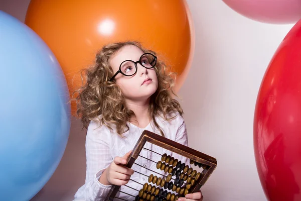 Thoughtful curly teen girl in glasses with wooden abacus on the — Stock Photo, Image