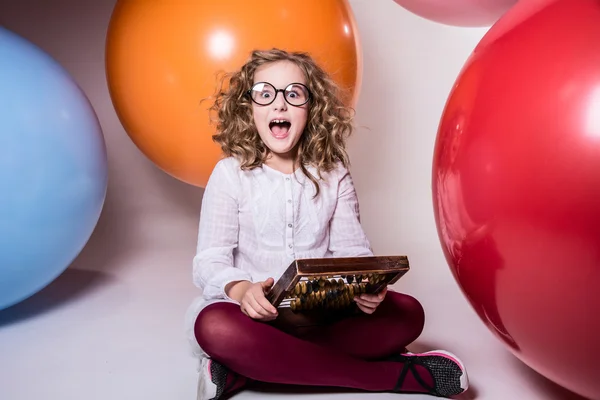 Screaming curly teen girl in glasses with wooden abacus on the b — Stock Photo, Image