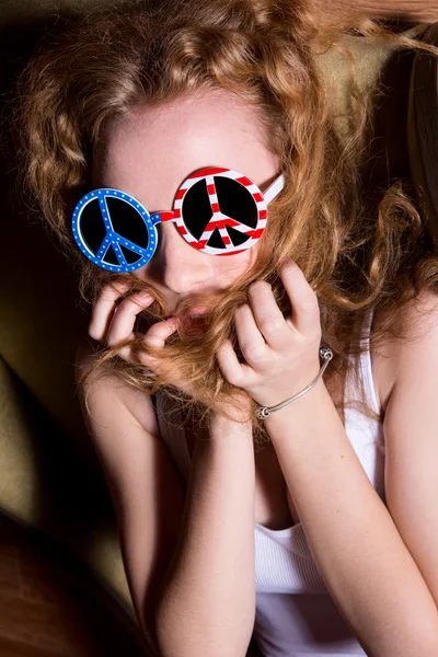 Mladá dívka s kudrnatými vlasy, nosí sluneční brýle s americkým — Stock fotografie