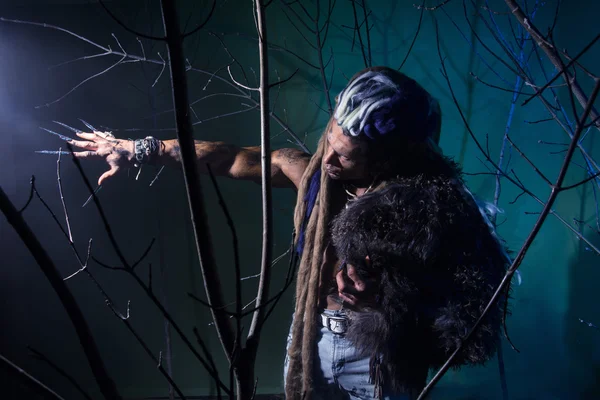 Homem musculoso com dreadlocks e pele através das árvores . — Fotografia de Stock