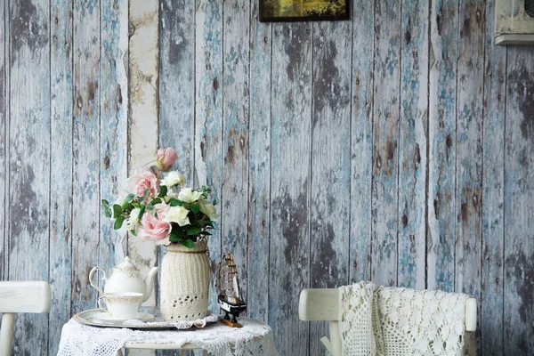 Porcelain teapot and cup on a table with a vase with artificial — Stock Photo, Image