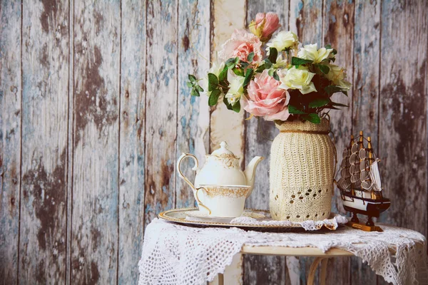 Porcelanowe czajnik i filiżanki na stole z wazon z sztuczne — Zdjęcie stockowe