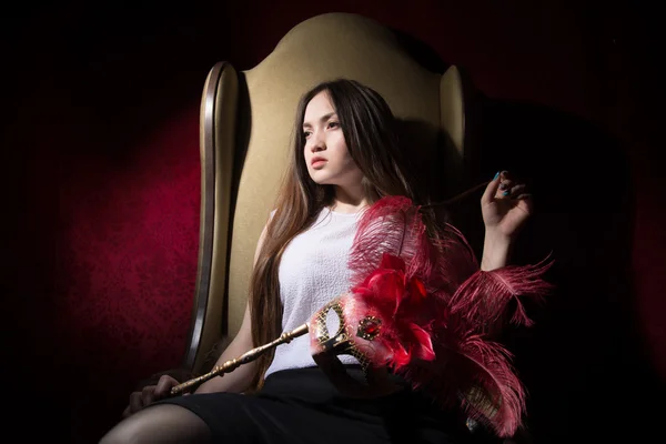 Asian girl sitting in a chair thoughtfully looks away. — Stock Photo, Image