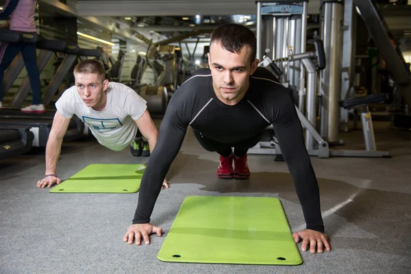 Zwei Männer arbeiten im Fitnessstudio an Gymnastikmatte. — Stockfoto