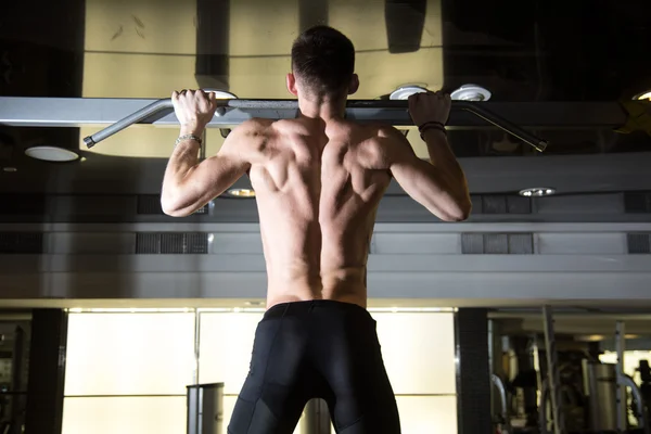 Hombre de fitness haciendo pull-ups en un gimnasio para un entrenamiento de espalda — Foto de Stock