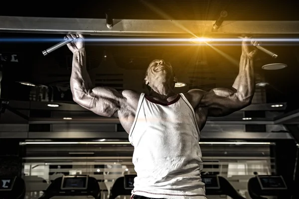 Schöner muskulöser Mann im Fitnessstudio, der Erhebungen macht. — Stockfoto