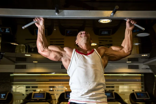 Muskelsportler Mann im Fitnessstudio macht Erhöhungen. — Stockfoto