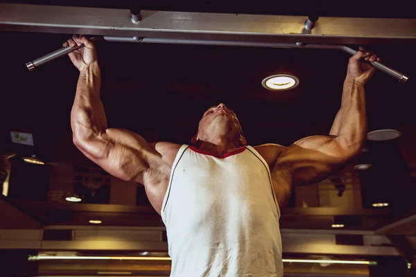 Schöner muskulöser Mann im Fitnessstudio, der Erhebungen macht. — Stockfoto