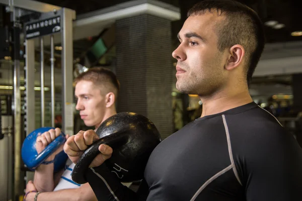 Kettlebell swing opleiding van twee jonge mannen in de sportschool — Stockfoto