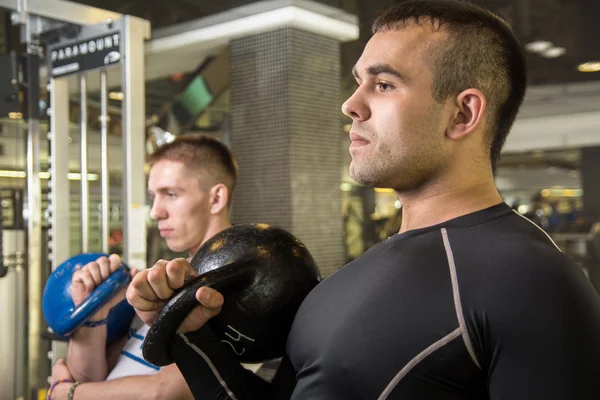 Kettlebell swing opleiding van twee jonge mannen in de sportschool — Stockfoto