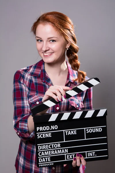 Piękny uśmiechający się rudowłosa kobieta trzymając kino klakier. — Zdjęcie stockowe