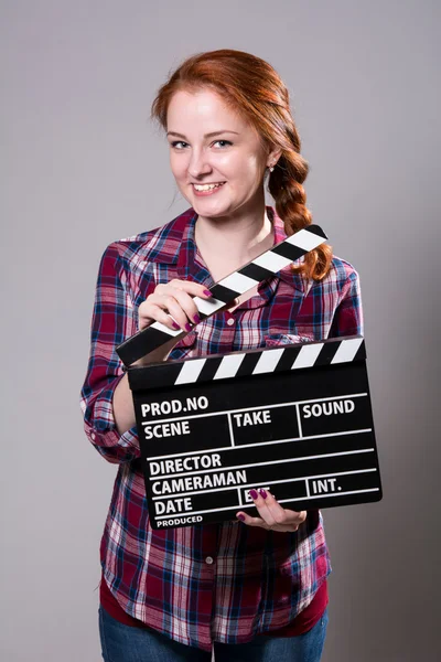 Hermosa mujer pelirroja sonriente sosteniendo un aplauso de película —  Fotos de Stock