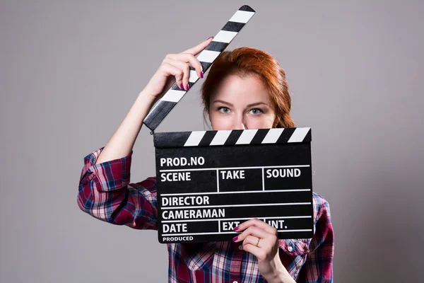 美丽的红头发女人抱着一个电影拍板，孤立奥雅纳 图库图片