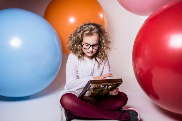 Thoughtful curly teen girl in glasses with wooden abacus on the — Stock Photo, Image