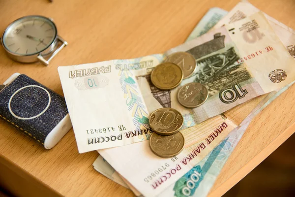 Russische geld en klok liggen op een houten tafel — Stockfoto